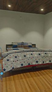 a bed with a comforter with stars on it at River side cafe guest cottage in Shamshi +3 photos