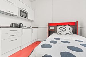 a bedroom with a bed and a kitchen with white cabinets at Compact Studio for , Kitchen, WiFi, Parking in Dudley in Dudley