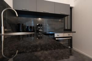 a kitchen with a black counter top and a sink at Le Passion Room - Love Room - Jacuzzi in Beauvais