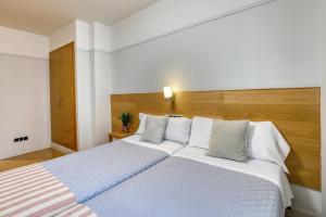 a bedroom with a large bed with white sheets and pillows at Mayor 71- El Hostalito in El Burgo de Osma