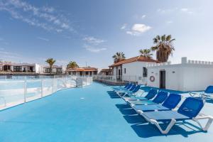 a row of blue lounge chairs on a swimming pool at Casa Mariposa in Caleta De Fuste