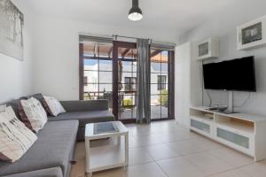 a living room with a couch and a flat screen tv at Casa Mariposa in Caleta De Fuste