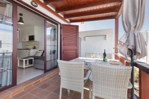 a patio with a table and chairs on a balcony at Casa Mariposa in Caleta De Fuste