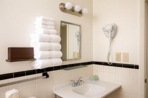 a bathroom with a sink and a stack of towels at Ventura Motel in Ludington +31 photos