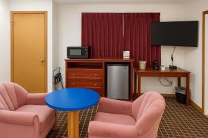 a room with two chairs and a table and a tv at Ventura Motel in Ludington