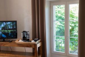 Zimmer mit einem Fenster und einem Schreibtisch mit einem TV. in der Unterkunft Auberge de la Croix Blanche in Villarepos