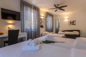 a hotel room with two beds and a table with towels at Hotel Riviera in Melide