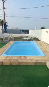 une piscine bleue dans une cour avec de l'herbe verte dans l'établissement Casa Pé na Areia Praia de Piratininga, à Niterói
