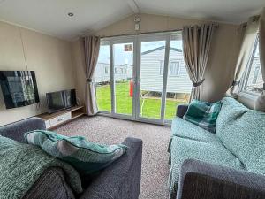 een woonkamer met een bank en een tv en een glazen schuifdeur bij Caravan In Scratby, Norfolk Ref 50071D in Great Yarmouth