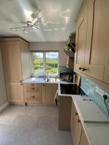 a kitchen with wooden cabinets and a sink and a window at Granite House in Carsphairn