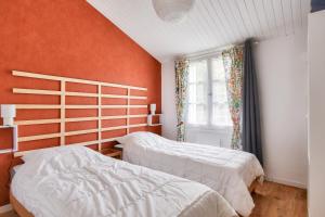 two beds in a bedroom with an orange wall at Jardin - Centre Noirmoutier - Maison pour 4 in Noirmoutier-en-l'lle