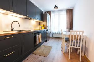 Una cocina con gabinetes negros y una mesa y sillas. en Apartament Danusia, en Kołobrzeg
