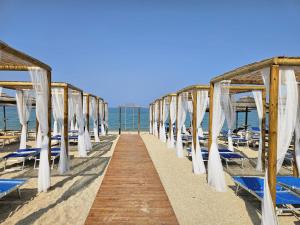 a row of white umbrellas and chairs on a beach at Appartamento Estivo in Porto Potenza Picena