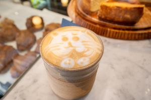 a cup of coffee with a face drawn on it at The Tropicana Hotel in Cape Town