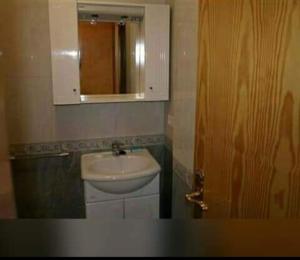 a bathroom with a sink and a mirror and a door at Apartamento Studio in Rianjo