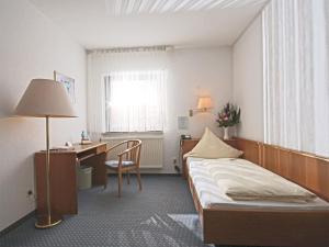 ミヒェルシュタットにあるCity Hotel Mark Michelstadtのベッドとデスクが備わるホテルルームです。
