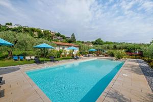 a swimming pool with blue umbrellas in a yard at Agriturismo Il Cardo in Soiano del Lago