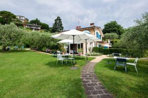 a table and chairs with an umbrella on a lawn at Agriturismo Il Cardo in Soiano del Lago