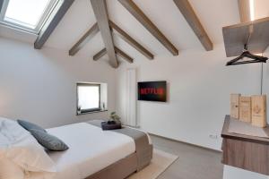 a white bedroom with a bed and a tv at Centro Storico Cormons - Luxury Design and Comfort in Cormòns