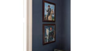 three framed paintings on a blue wall in a room at Jesse James - Historic Hotel in Cimarron