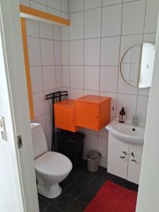 an orange cabinet in a bathroom with a toilet and sink at Appartement calme et central sur Bergen in Bergen