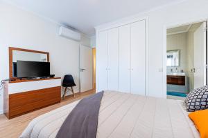 1 dormitorio con cama y vestidor con TV en Atlantic Breeze Apartment, en Armação de Pêra