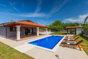 a swimming pool with chairs and a house at Villa Eni by Istrialux in Žminj