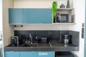 a kitchen with blue cabinets and a sink at Get By Side by Quarto à Vista in João Pessoa
