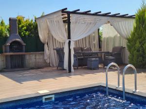 a pergola over a pool with a table and a grill at Villa Da London in Dalaman