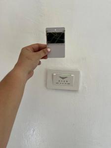 a persons hand manipulating a lightswitch on a wall at Sapayag Backpacker's Inn in Dipolog