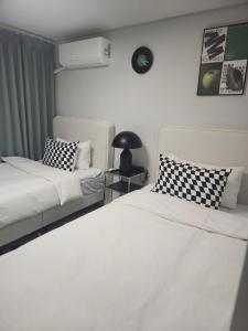 a bedroom with two beds and a table with a lamp at Stay Chic 황리단길 룸3 침대5 에어컨4 에어랩 건식사우나 동궁과월지 in Gyeongju