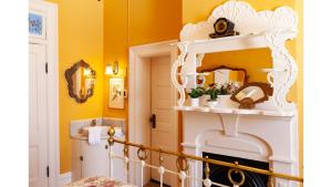 a room with yellow walls and a white fireplace at Mary Lambert - Historic Hotel in Cimarron