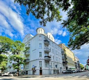 a large white building on a city street with cars at Stacja Jeżyce Pokój #B in Poznań