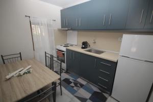 a kitchen with blue cabinets and a table and a refrigerator at Anna Cozy Corner in Agios Nikolaos