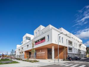 - un bâtiment blanc dans une rue avec un ciel bleu dans l'établissement Zenitude Hôtel-Résidences Chambéry, à Chambéry