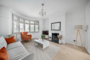 ein weißes Wohnzimmer mit einer Couch und einem Tisch in der Unterkunft Spacious 4BR House with Parking, Garden & 500Gb WiFi in London