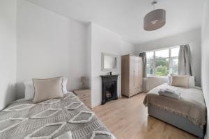 ein weißes Schlafzimmer mit einem Bett und einem Kamin in der Unterkunft Spacious 4BR House with Parking, Garden & 500Gb WiFi in London