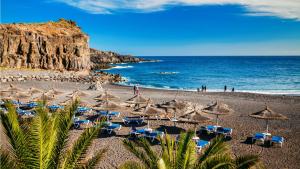 una spiaggia con sedie e ombrelloni e l'oceano di Tranquil 4 Bedroom Holiday Villa a Callao Salvaje