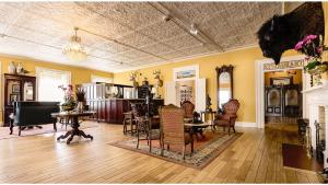 a large living room with chairs and a piano at William F Cody - Historic Hotel in Cimarron