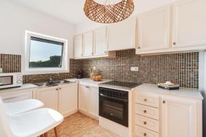 a kitchen with white cabinets and a sink and a window at Villa Luciana - Radiante casa vecina del mar in Son Bou