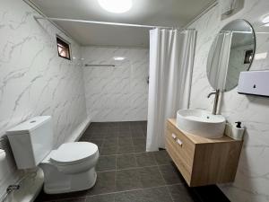 a white bathroom with a toilet and a sink at Urban Grace in Bangkok
