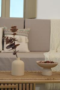 a white vase and a bowl on a coffee table at Vento Apartment in Astypalaia Town