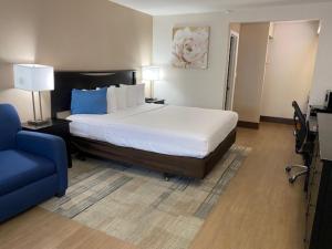 een slaapkamer met een groot bed en een blauwe stoel bij Stanford Inn & Suites Anaheim in Anaheim