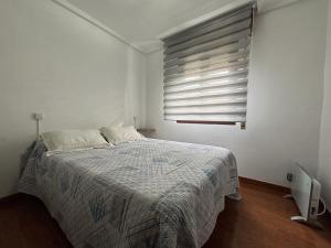 a white bedroom with a bed and a window at Ortuella Apartment in Ortuella