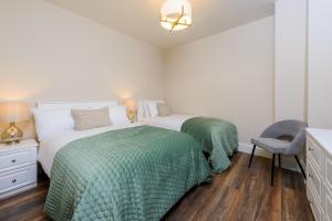 a bedroom with two beds with green sheets and a chair at Dingle Heritage Townhouse in Dingle