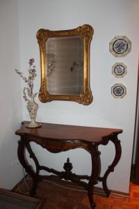 a table with a mirror and a vase on it at Coroneo33 - Spazioso per famiglie - NaonBnB in Trieste