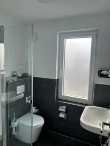 a bathroom with a toilet and a sink and a window at Hotel Restaurant Harrier Hof in Brake