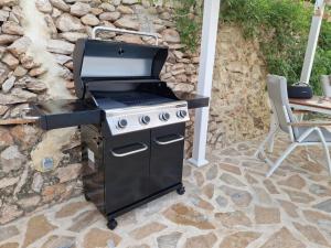 a barbecue grill on a patio next to a stone wall at Renovierte Villa mit privatem Pool fußläufig zum Meer in Benissa