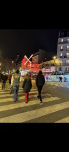 a group of people walking across a street at night at Le secret du Moulin in Paris +1 photo