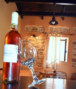 a bottle of wine and a wine glass on a table at Tilemachos Traditional House in Vathi